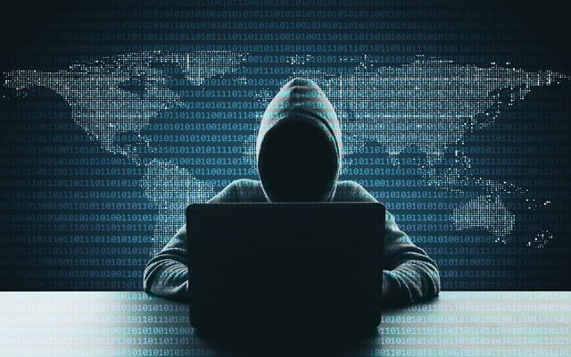 Hacker in hoodie using laptop, symbolizing global cybersecurity threats in 2025.
