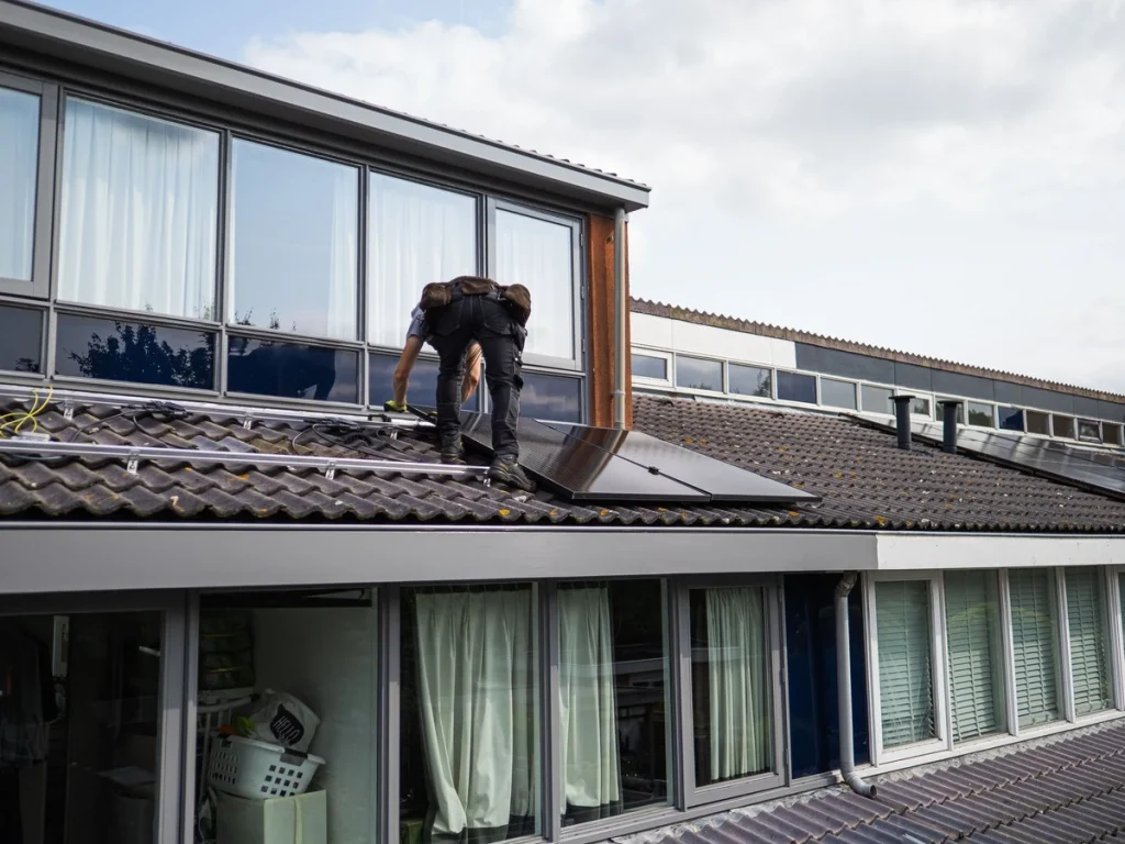 Solar installer mounting one of the different types of solar panels on a residential rooftop.